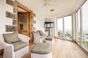 a living room with chairs and a tv and windows at Seaview Penthouse 1 in Alnmouth