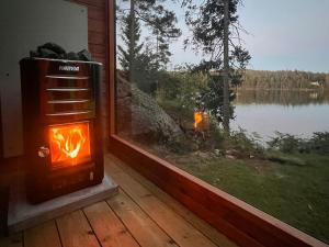 a stove in a room with a view of a lake at Mini House With Sandy Beach And Sauna in Olofstorp +13 photos