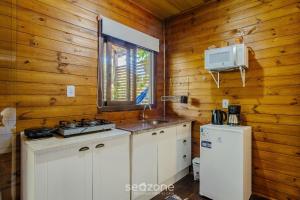 een keuken met een fornuis en een wastafel in een huisje bij Chalés Elegantes e Completos em Imbituba - REL in Praia do Rosa