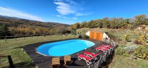 a swimming pool with chairs and a wooden deck at Fount de Cousteno in Limbrassac
