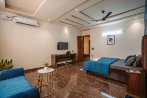 une chambre avec un lit, un canapé et une télévision dans l'établissement Hotel Golf Sakura, à Gurgaon