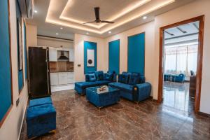 un salon avec des meubles bleus et un ventilateur de plafond dans l'établissement Hotel Golf Sakura, à Gurgaon 2 autres photos