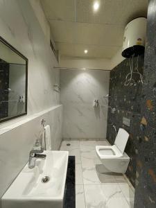 une salle de bain blanche avec un lavabo et des toilettes dans l'établissement Hotel Golf Sakura, à Gurgaon