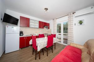 a kitchen and dining room with red cabinets and a table at Apartmani Andreja in Pag