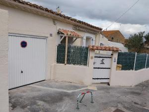 a white house with a gate and a garage at Les aires in Tourbes