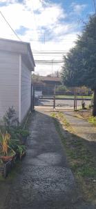 eine Auffahrt neben einem Haus mit einem Zaun in der Unterkunft Cabaña interior en el centro de llanquihue in Llanquihue