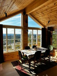 a dining room with a table and chairs and large windows at Mountain Cabin With Panoramic Views In Valdres in Bruflat