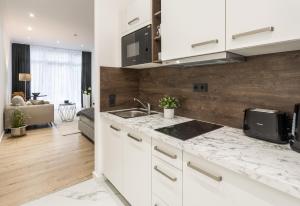 a kitchen with white cabinets and marble counter tops at Ferienwohnung Salinenparc Design Budget Hotel in Erwitte