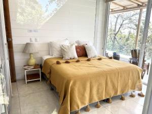 une chambre avec un grand lit avec une grande fenêtre dans l'établissement Ocean View Jungle Nest - 2min From The Beach, à Santa Teresa