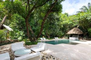 - une piscine avec des chaises blanches et un complexe dans l'établissement Ocean View Jungle Nest - 2min From The Beach, à Santa Teresa