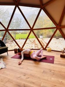 Eine Frau, die auf dem Boden liegt und eine Yoga-Pose macht. in der Unterkunft La bulle d'Ostara 