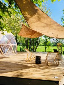 eine Holzterrasse mit 2 Stühlen und einem Zelt in der Unterkunft La bulle d'Ostara  + 21 Fotos