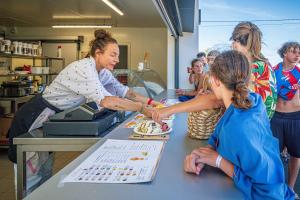 eine Gruppe von Frauen steht um einen Tisch herum und schneidet einen Kuchen in der Unterkunft Camping Saint-Hilaire-de-Riez in Saint-Hilaire-de-Riez + 9 Fotos