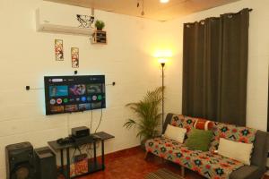 a living room with a couch and a flat screen tv at Las Palmeritas in Ahuachapán