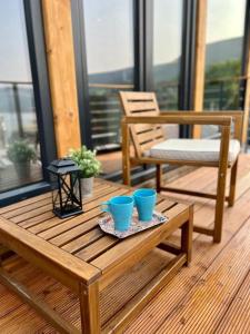 a wooden table with two blue cups on a balcony at Mountain Log Cabin in Mavrovo