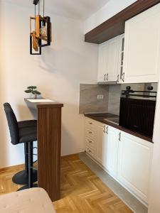 cocina con armarios blancos, mesa y taburete en Apartman Banjac, en Vrnjci