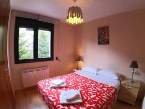a bedroom with a red and white bed with towels on it at Soldeu Paradis La Solana in El Tarter