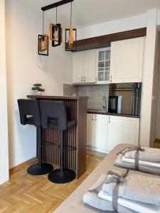 una cocina con armarios blancos y un bar con taburetes negros en Apartman Banjac, en Vrnjci