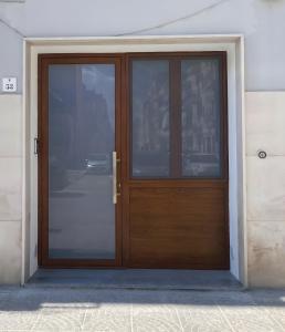 une porte en bois avec des panneaux de verre sur un bâtiment dans l'établissement Emmeci House, à Alghero