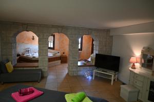 ein Wohnzimmer mit einem Bett und einem Fernseher in der Unterkunft Tranquil Infinity Pool Getaway (private jacuzzi and steam bath, pool, garden, sea and city views) in Volos