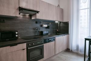 a kitchen with wooden cabinets and a stove and a sink at Glamour Jacuzzi Privé Chambéry in Chambéry +17 photos