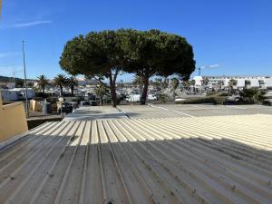 Appt Studio 2 couchages CAP D'AGDE NATURISME في كاب داغد: شجرة على قمة مبنى مع رصيف