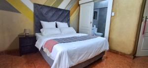 a bedroom with a large bed with a large headboard at Neema Lodge in Boksburg +8 photos