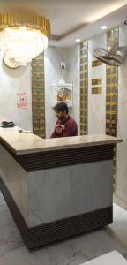 a man sitting at a counter in a room at aluxor hotel and Restaurant in Kharar