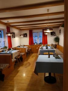 ein Restaurant mit mehreren Tischen in einem Raum mit roten Vorhängen in der Unterkunft B&B Garni Lantschner in Kastelruth