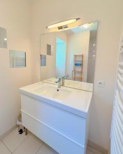 a bathroom with a white sink and a mirror at Du soleil au balcon - Hypercentre in Lons-le-Saunier +11 photos