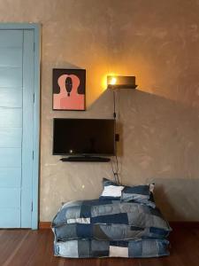 a bedroom with a bed and a flat screen tv at The Urban Farm House in Accra