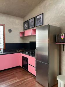 a kitchen with pink cabinets and a stainless steel refrigerator at The Urban Farm House in Accra