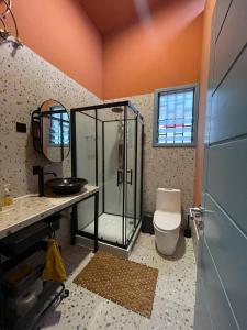 a bathroom with a shower and a toilet and a sink at The Urban Farm House in Accra