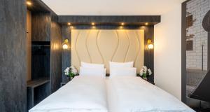 a bedroom with a large white bed with white pillows at PLAZA Premium Parkhotel Neu-Ulm in Ulm