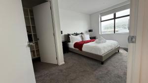 a white bedroom with a bed and a window at Stylish Cashel Townhouse Stay in Linwood