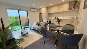 a living room with a couch and a table and chairs at Stylish Cashel Townhouse Stay in Linwood