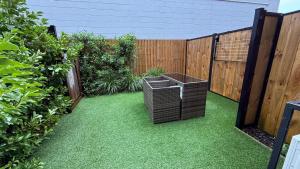 a garden with a wicker trash can on the grass at Stylish Cashel Townhouse Stay in Linwood
