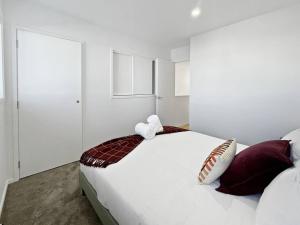 Chic 1-Bedroom Apartment with Balcony in Ferry Rd في Linwood: غرفة نوم بسرير أبيض كبير مع وسائد حمراء