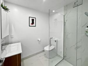 Chic 1-Bedroom Apartment with Balcony in Ferry Rd في Linwood: حمام ابيض مع مرحاض ودش زجاجي +3 صور