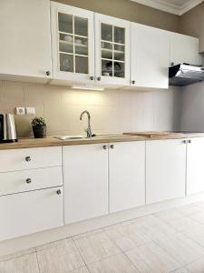 Una cocina con gabinetes blancos y un fregadero. en Summertime, en Porches