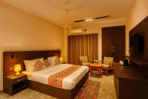 a hotel room with a bed and a television at The Four Season - A boutique Wellness Cottage by Aura in Haridwar in Haridwār
