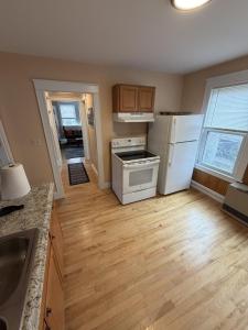 a kitchen with white appliances and a wooden floor at The Coastal Connection in South Portland