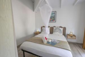 a bedroom with a white bed with a book on it at L'Escapade Créole in Saint-François +83 photos