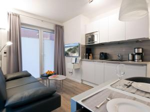 Una sala de estar con un sofá y una cocina. en Palais Garteneck 4, en Norderney