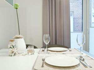 Una mesa con platos y vasos blancos y una ventana. en Palais Garteneck 4, en Norderney