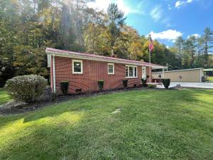a red brick house with a flag in a yard at Deer Run Creek Cottage in Mountain City