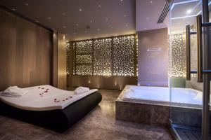 a bath room with a tub and a shower at Pietre Nere Resort & Spa in Modica