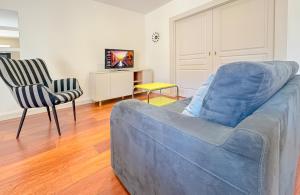 a living room with a blue couch and two chairs at Du soleil au balcon - Hypercentre in Lons-le-Saunier