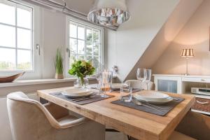 a dining room with a wooden table and chairs at Haus Weesterhuk, Whg 8 Jopi Keitum in Keitum +16 photos