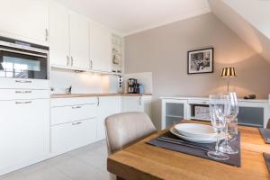a kitchen with a wooden table and white cabinets at Haus Weesterhuk, Whg 8 Jopi Keitum in Keitum